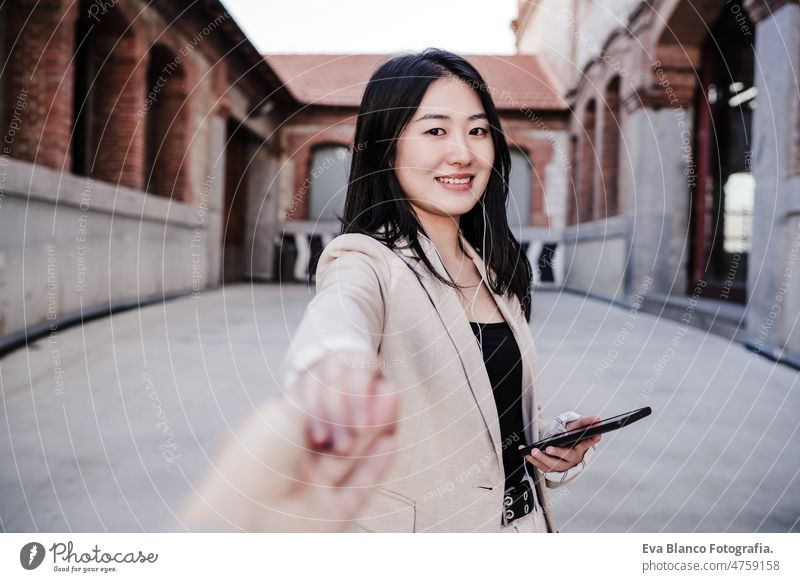 selbstbewusste schöne chinesische Geschäftsfrau, die in der Stadt ein Mobiltelefon benutzt und einen Freund an der Hand hält. POV Händchen haltend Chinesisch