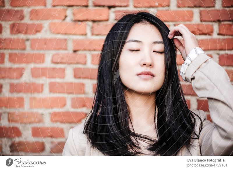entspannt schöne chinesische Geschäftsfrau stehend über Ziegel Wand Hintergrund mit geschlossenen Augen Augen geschlossen Chinesisch asiatisch Frau Laptop