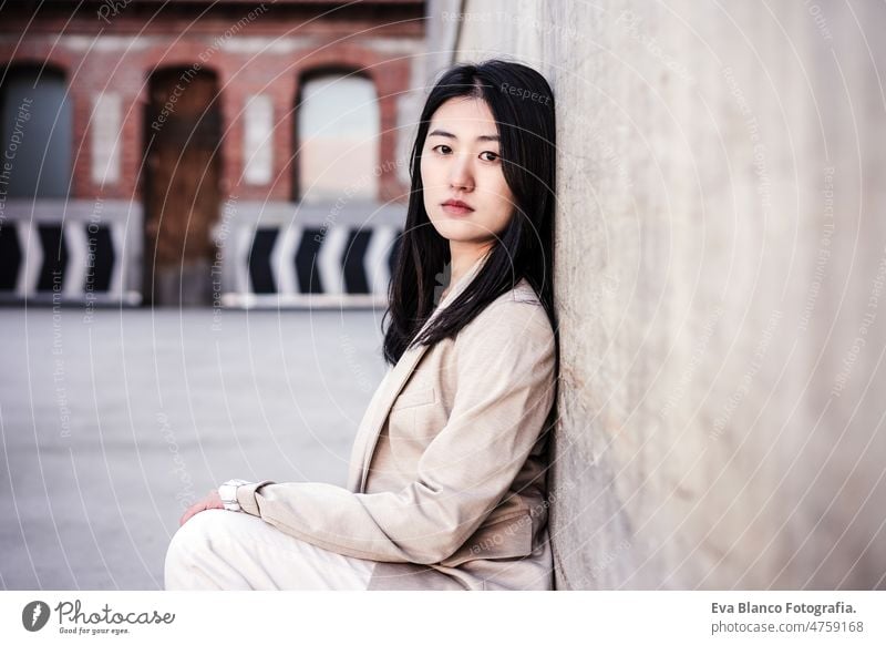 Porträt einer selbstbewussten chinesischen Frau in der Stadt, die sich an eine Wand lehnt Chinesisch Großstadt Lifestyle modern Business Unternehmer asiatisch