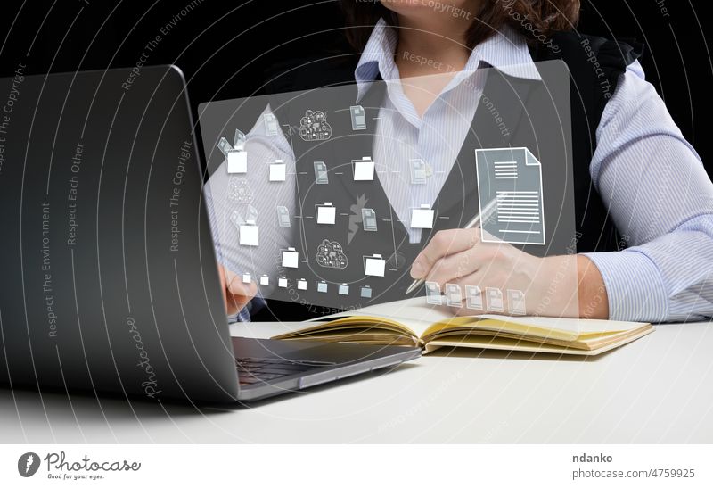 Frau sitzt an einem Tisch und arbeitet mit einem Laptop. Dokumentenmanagement-System (DMS). Software zur Automatisierung der Archivierung und effizienten Verwaltung von Informationsdateien