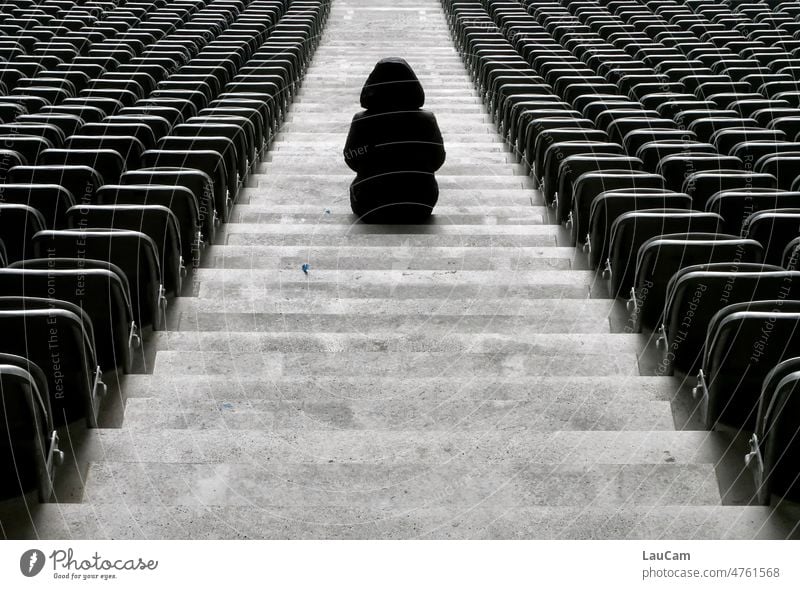 Geisterspiel - eine einsame Gestalt sitzt auf der Treppe eines leeren Stadions leere Plätze Person leere Ränge Geisteespiel Sport Schwarzweißfoto trist düster