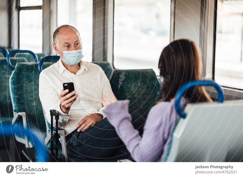 Ein befreundetes Paar trägt eine Maske und unterhält sich während einer Zugfahrt reisen Mundschutz Frau sich[Akk] unterhaltend reden Talkrunde Frauen Mann