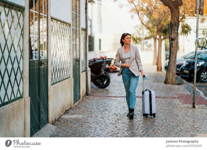 Porträt einer reisenden Frau mit Gepäck in der Stadt Großstadt covid-19 COVID medizinisch schützend Pandemie Mundschutz erkunden Schüler Geschäftsmann Abenteuer