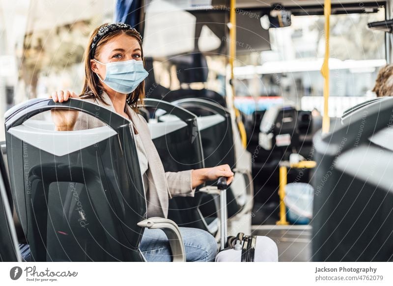 Eine junge Frau mit Maske, die mit dem öffentlichen Bus pendelt Reisender Pandemie Mundschutz Erwachsener Ausflug Auto Fahrzeug lässig Lächeln Laufwerk Sitzen