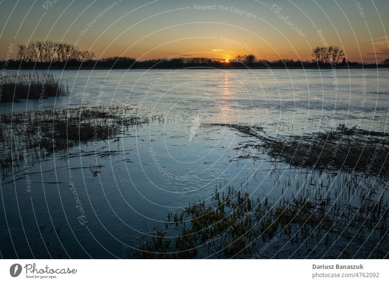 Abendlicher Blick auf einen vereisten See bei Sonnenuntergang, Stankow, Polen Eis Wasser im Freien Natur Himmel Winter Schilfrohr blau horizontal Fotografie
