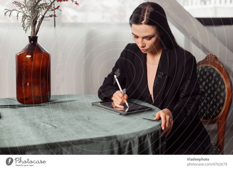 Junge brünette freiberufliche Designerin zeichnet Skizzen auf einem Grafiktablett mit einem Stylus Frau zeichnen Arbeit Innenbereich Klassik Tablette Griffel