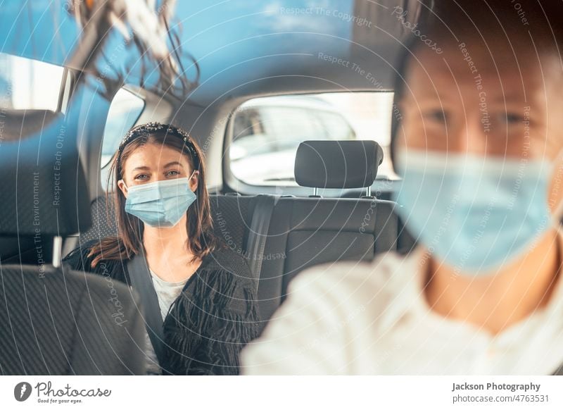 Eine Frau mit einer Schutzmaske auf dem Rücksitz eines Taxis PKW Tourist Passagier Fahrer uber Klient Reflexion & Spiegelung privat Lächeln Glück entdecken