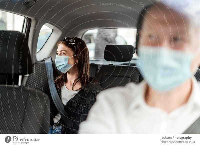 Eine Frau mit einer Schutzmaske auf dem Rücksitz eines Taxis PKW Tourist Passagier Fahrer uber Klient Reflexion & Spiegelung privat Lächeln Glück entdecken