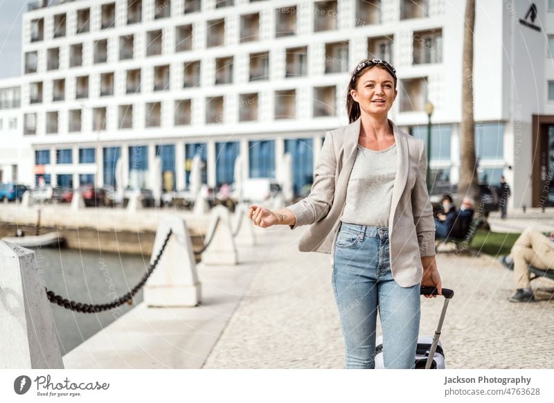 Ein Porträt einer jungen, glücklichen Frau, die mit dem Gepäck in der Stadt spazieren geht Tasche Reisender reisen Lächeln Straße Hotel Spaziergang Mode