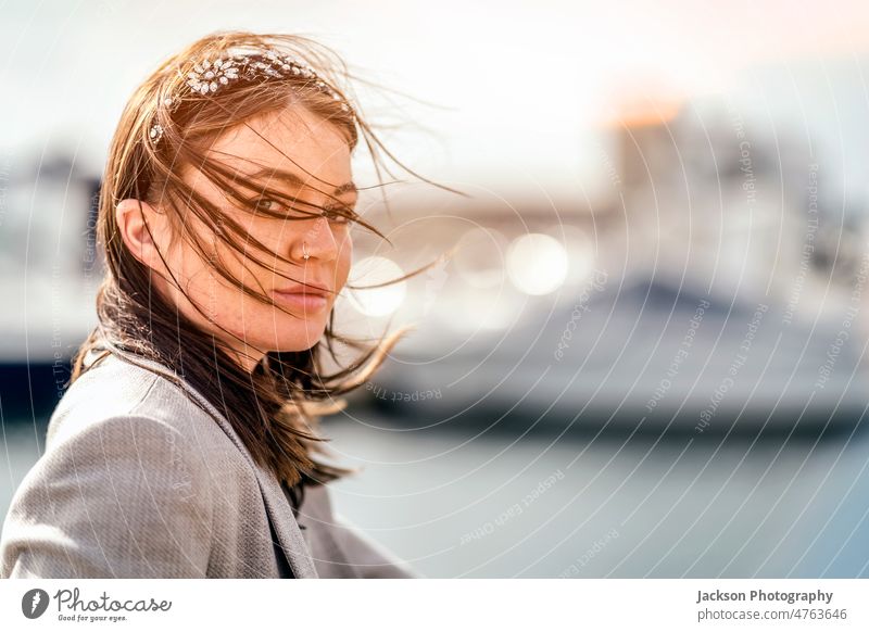 Ein Porträt einer attraktiven jungen Frau mit Haaren im Gesicht Wind windig verborgen Textfreiraum ernst Tierhaut Behaarung selbstbewusst im Freien unabhängig