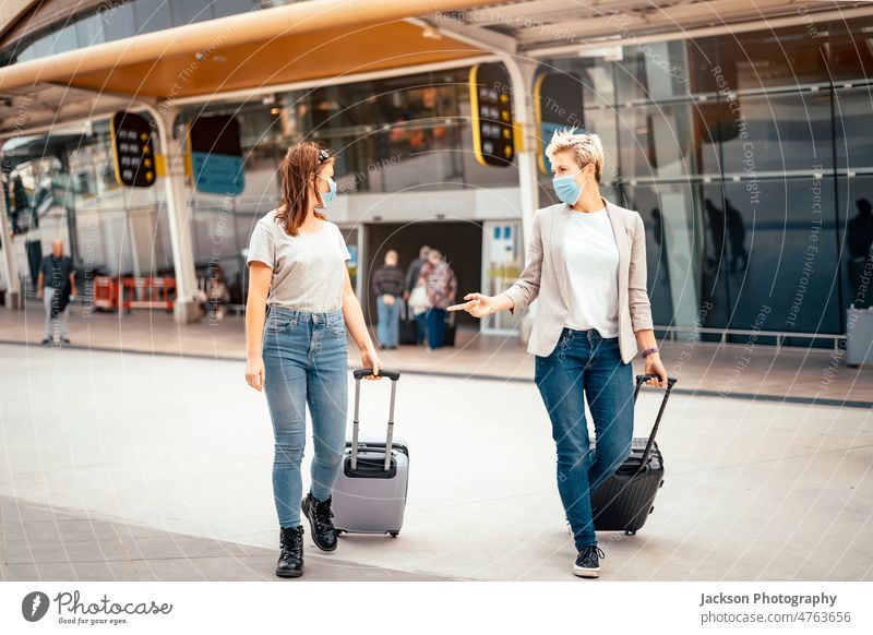 Reisende Frauen in Schutzmasken mit Gepäck im Gespräch auf dem Weg vom Flughafen reisen Freunde Mundschutz reden COVID covid-19 Pandemie Lifestyle Pendler