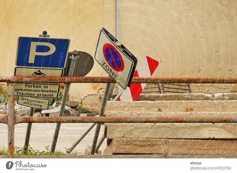 mehrere Verkehrszeichen und Zusatzschilder lehnen an einer Metallabsperrung neben Betonplatten / Lagerplatz für Straßenbaumaßnahmen Baumaßnahme Verkehrsschilder