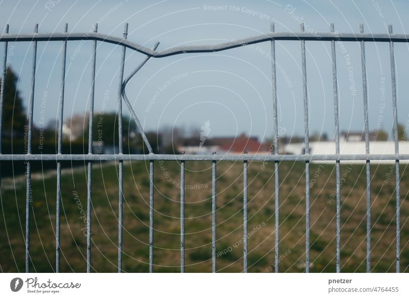 Ein Loch in einem Zaun Verbogen Feld Trennung Grenze Einbruch einbrechen biegen Stahl Draht Kraft Stadtrand Eindringen verboten Gewalt Sicherheit Barriere