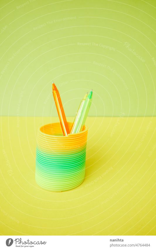 Bunte Stifte in einem bunten Slinky-Spielzeug slinky Fluor Farbe Kindheit erinnern retro orange grün Kalk gelb flach Hintergrund abstrakt chape kreisen Spirale