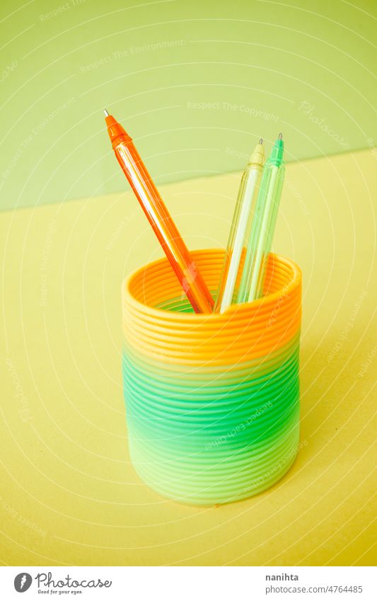 Bunte Stifte in einem bunten Slinky-Spielzeug slinky Fluor Farbe Kindheit erinnern retro orange grün Kalk gelb flach Hintergrund abstrakt chape kreisen Spirale