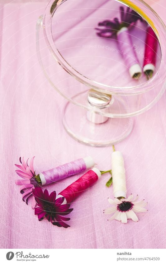 Stilleben mit Blumen, Nähgarn und einem Schönheitsspiegel in trendigen Saisontönen Nähen Faser Couture geblümt purpur Spiegel Palette Stillleben Design Trends