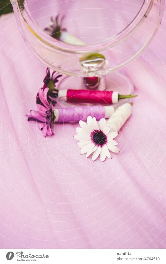 Stilleben mit Blumen, Nähgarn und einem Schönheitsspiegel in trendigen Saisontönen Nähen Faser Couture geblümt purpur Spiegel Palette Stillleben Design Trends