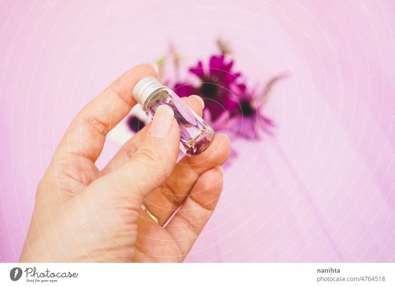 Nahaufnahme einer Hand, die eine mit Wasser und Blütenblättern gefüllte Aromatherapie-Flasche hält notwendig Erdöl geblümt Blume Blütenblatt Probe Frühling