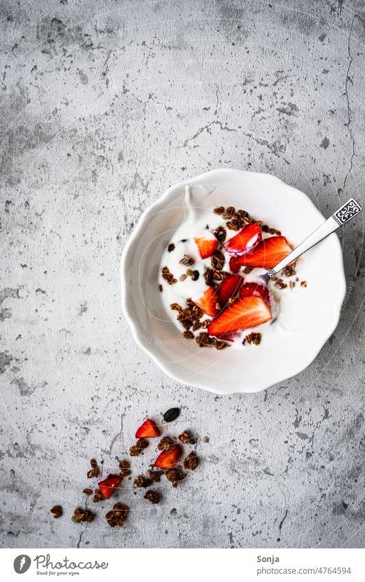 Eine Müsli Schüssel mit Joghurt und frischen Erdbeeren auf einem rustikalen Tisch. Draufsicht. Frühstück Dessert Frucht Diät organisch Gesundheit weiß Molkerei