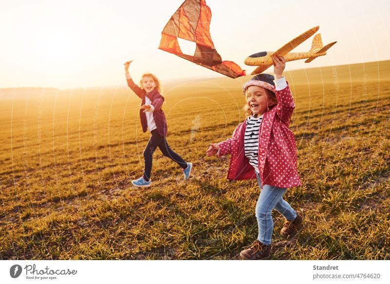 Zwei kleine Mädchen Freunde haben Spaß zusammen mit Drachen und Spielzeug Flugzeug auf dem Feld an sonnigen Tag Zusammensein Ebene Einheit Kinder spielen Milan
