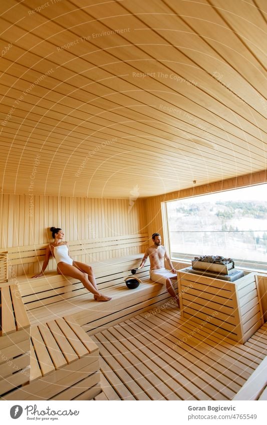Junges Paar entspannt sich in der Sauna und beobachtet den Winterwald durch das Fenster Erwachsener Bad Schönheit Körper Kabine Kaukasier Finnland Finnisch Wald