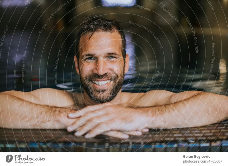 Porträt eines lächelnden jungen Mannes, der sich am Rande des Schwimmbads entspannt Junger Mann gutaussehender Mann hübscher junger Mann Beckenrand männlich
