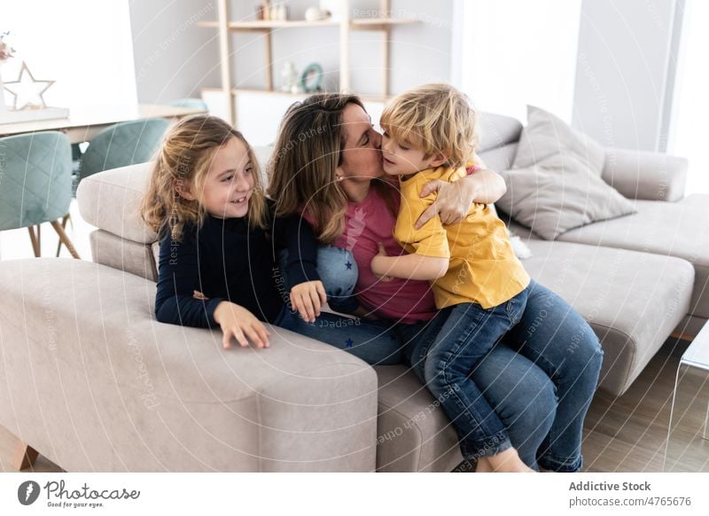 Mutter küsst Sohn in der Nähe der Tochter Kinder Geschwisterkind Zeitvertreib Zeit verbringen Wohnzimmer Liebe Kindheit Kuss Streicheln Mutterschaft Bonden