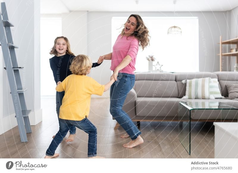 Fröhliche Mutter mit herumwirbelnden Kindern Geschwisterkind spielen Zeitvertreib Zeit verbringen Wohnzimmer Kindheit sich im Kreise drehen Spaß haben