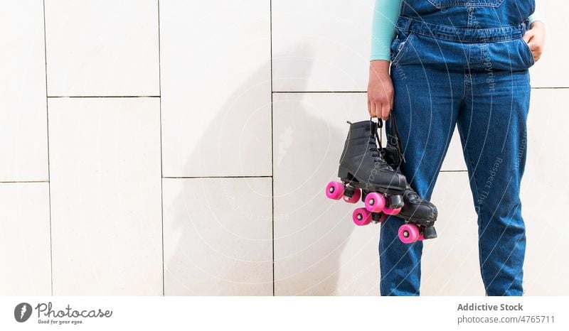 Anonyme Frau, die Rollen gegen eine Hauswand trägt Rollerskate Vierfachrolle Schlittschuh Hobby sportlich Wand Lifestyle aktiv Fliesen u. Kacheln Aktivität