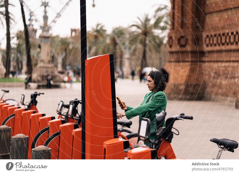 Konzentrierte Frau, die für einen Fahrradverleih bezahlt bezahlen Miete Terminal Teilen Straße Öffentlich Verkehr System automatisieren Smartphone Großstadt
