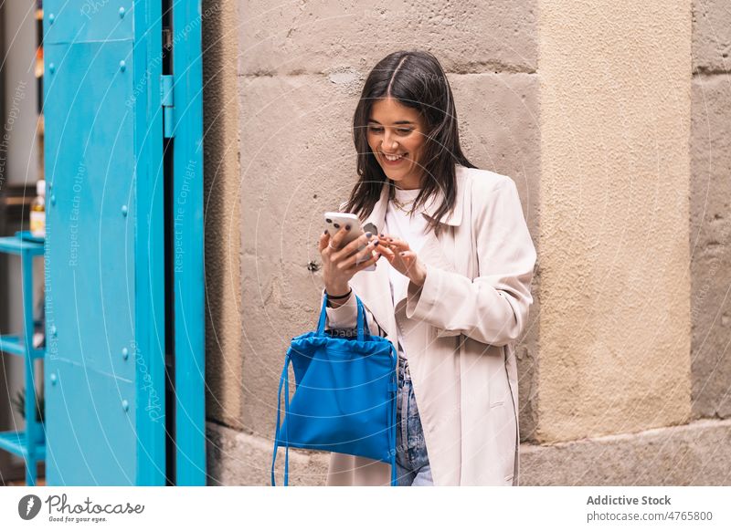 Fröhliche Frau, die auf der Straße ihr Smartphone durchsucht Browsen Textnachricht online Internet Großstadt urban soziale Netzwerke Vorschein Stadt Dame