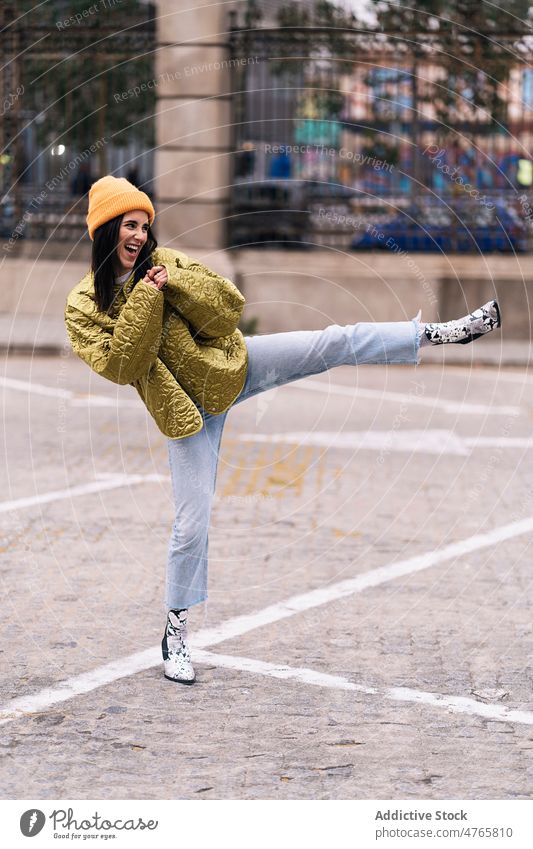 Frau macht Bein Kick auf der Straße Großstadt urban Vorschein üben Fähigkeit ausführen Energie heiter froh Kopfbedeckung positiv Lächeln Bürgersteig Inhalt