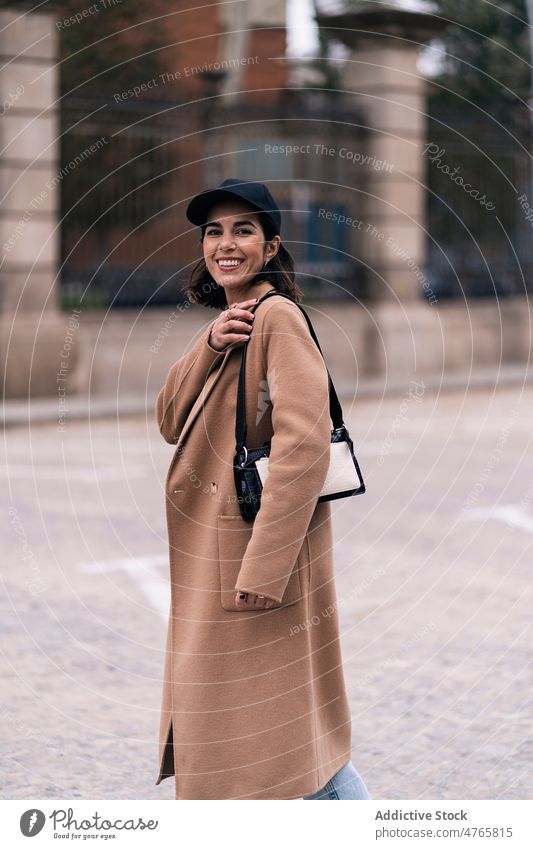 Positive Frau im Mantel auf der Straße Stil Großstadt Outfit trendy Mode urban Vorschein feminin Glück heiter Handtasche Verschlussdeckel froh Kopfbedeckung