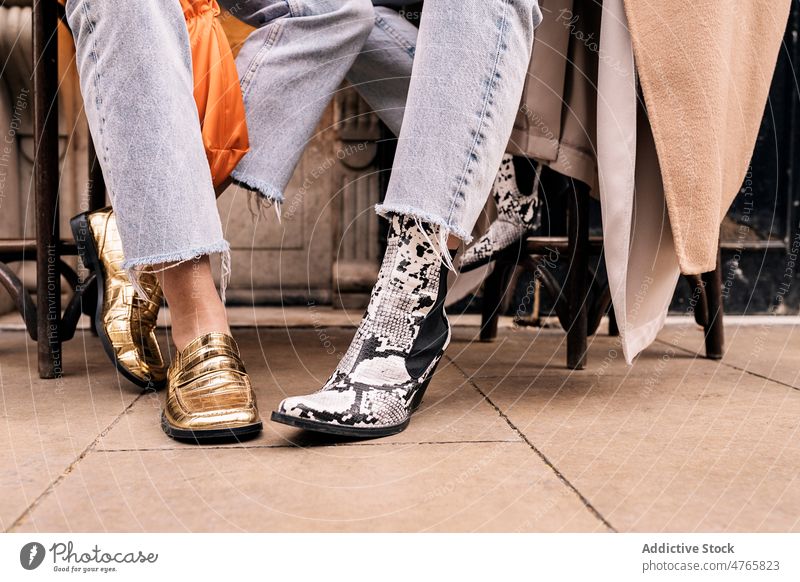 Unbekannte Frauen sitzen auf der Straße Freund Schuhe Stil Design Stilrichtung Großstadt Mode urban Jeanshose Bein Zusammensein Freundschaft Stuhl trendy modern