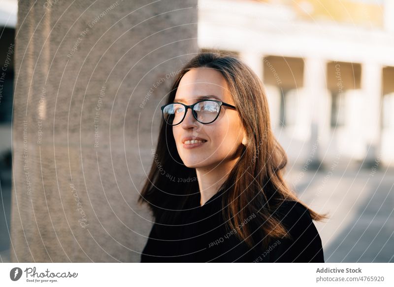 Lächelnde Frau mit Brille bewundert die sonnige Straße positiv bewundern Glück Individualität Porträt sorgenfrei charmant verträumt tausendjährig Sonnenlicht