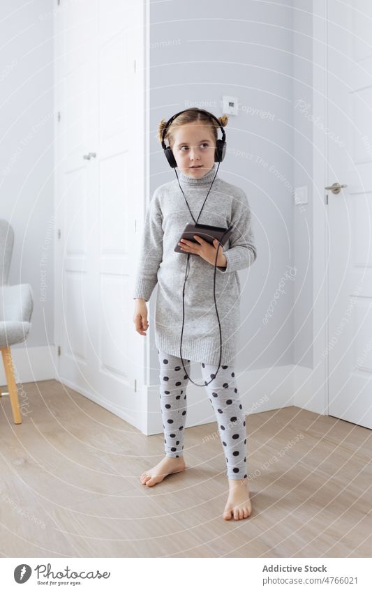 Neugieriges Mädchen mit Tablet, das mit Kopfhörern Musik hört benutzend zuhören Wiedergabeliste digital Tablette Süchtige Freizeit abhängig Gerät Starrer Blick