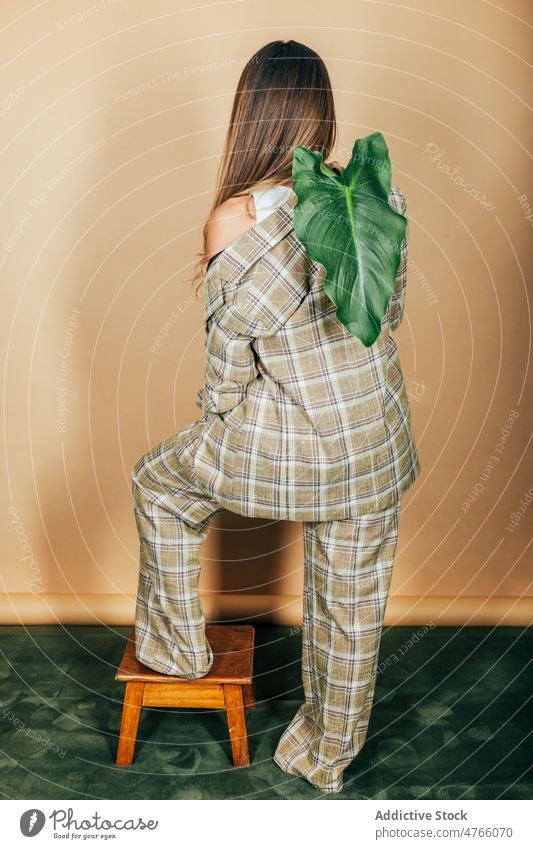 Frau im eleganten Anzug mit grünem Zweig im Studio Model Stil formal Blatt trendy kariert stilvoll Pflanze Atelier Jacke Studioaufnahme feminin Outfit