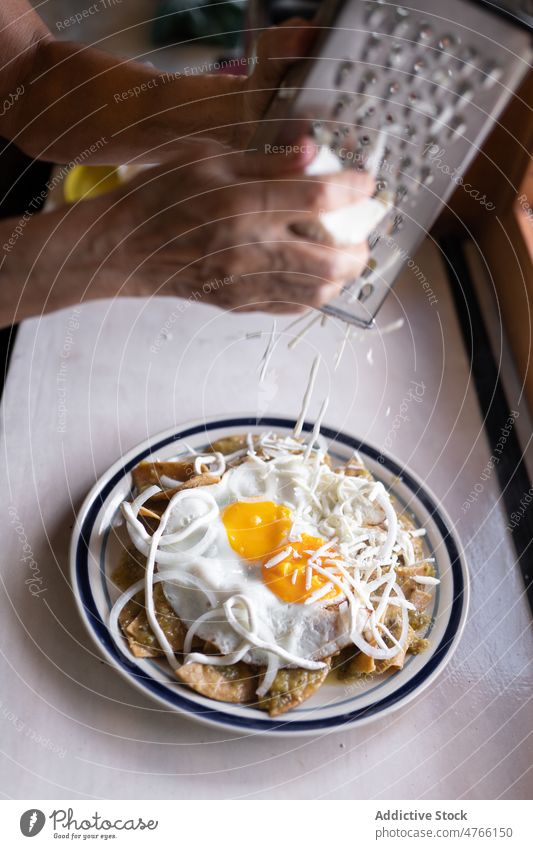 Unbekannte Person reibt Käse auf Essen mit Eiern und Nachos Koch Speise kulinarisch Mahlzeit nachos Tortilla Küche gebraten Gitter mexikanisches Essen dienen