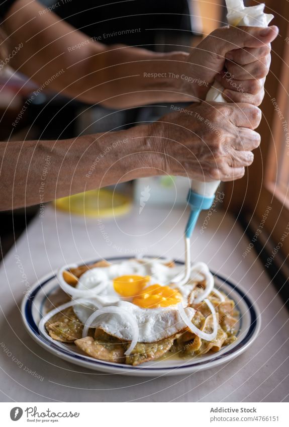 Anonyme Person gießt Soße auf Teller mit Spiegeleiern und Nachos Koch Speise kulinarisch Mahlzeit Ei nachos Tortilla Küche gebraten dienen Saucen eingießen