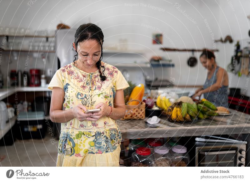 Mexikanische Frau, die in der Küche eines Cafés auf ihrem Smartphone surft mexikanisch Textnachricht Browsen online Mitarbeiterin Internet Talkrunde hispanisch