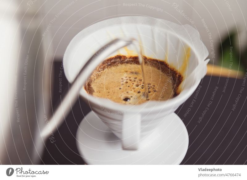 Der Barista gießt kochendes Wasser auf und brüht gemahlenen Kaffee, der in einen Papierfilter gefüllt wird. Gießen heiß brauen Topf elektronische Waage Skala