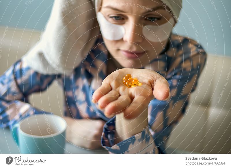 Nahaufnahme einer Frau mit einer Pille Lebertran Omega-3. Sie hält eine Weichschalen-D-Vitamin-Kapsel in der Hand. Diät Ernährung und gesundes Konzept. Selektiver Fokus. Vitamin E, A Fischöl