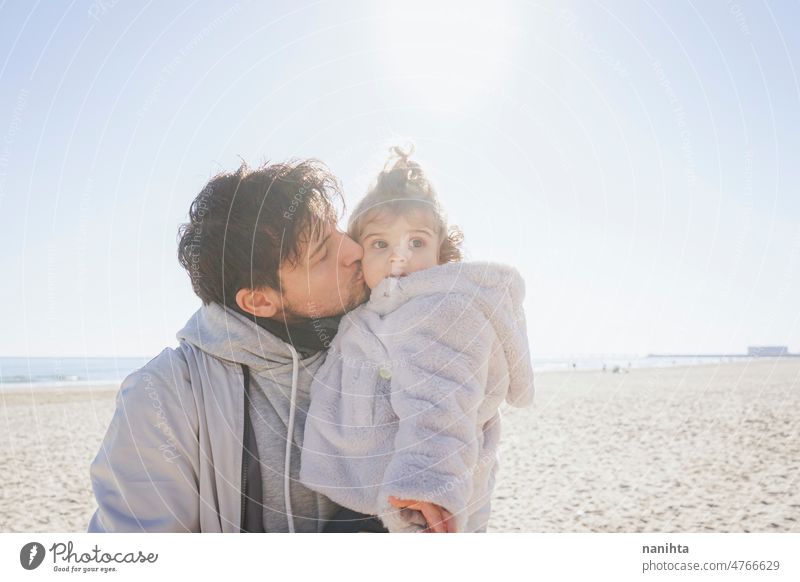 Alleinerziehender Vater trägt sein Baby an einem sonnigen Tag Single Eltern Familie Zuneigung Kleinkind Papa Umarmung führen Mädchen Tochter Strand Winter