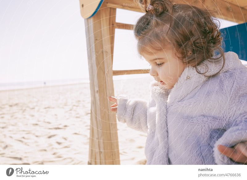 Kleines Mädchen genießt einen sonnigen Wintertag auf dem Spielplatz am Strand Kleinkind Glück neugierig spielerisch erkunden Familie Sonne bezaubernd lieblich