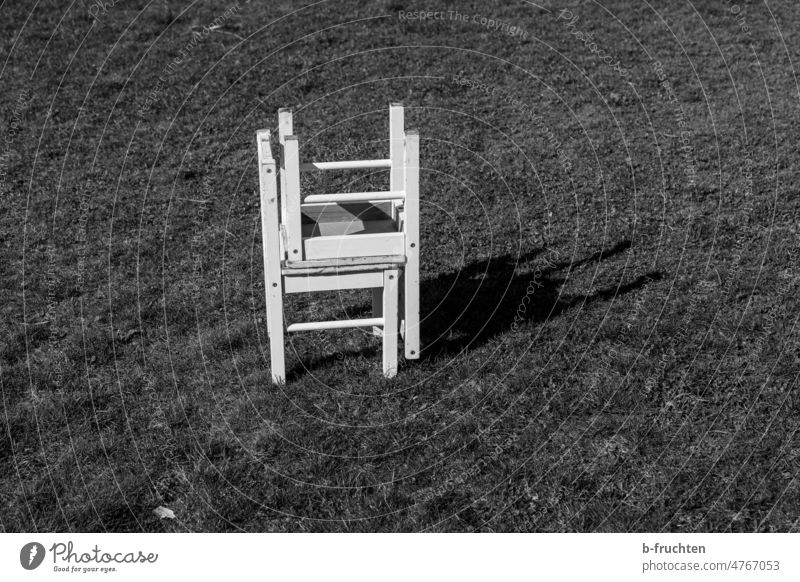 Zwei kleine weiße Holzstühle aufeinander gestapelt Stühle Sessel Sitzgelegenheit Möbel Menschenleer Stuhl sitzplatz Gras Wiese stehen alleine Schwarzweißfoto
