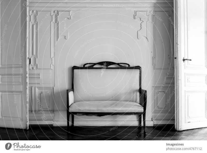 Vintage Sofa, Sessel im leeren Raum mit Wandhintergrund aus Stuckelementen. Wohnzimmer mit antikem, stilvollem Sessel an der Wand in der Mitte von zwei alten Türen. Flachrelief Stuckleisten Rokoko-Elemente