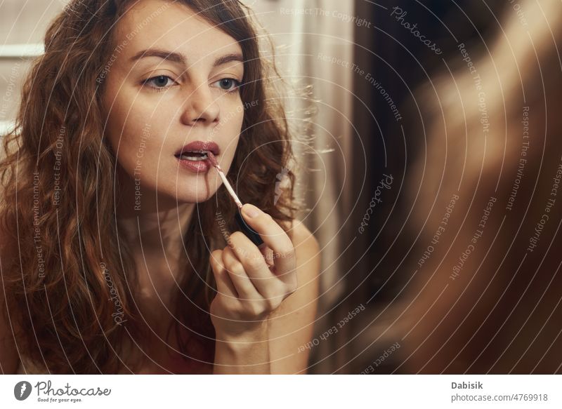 Frau trägt Make-up vor einem Spiegel auf Lippenstift Schönheit Selbst lockig Porträt Gesicht kometisch kleben Model Mund Lippenpflege Haut Pflege
