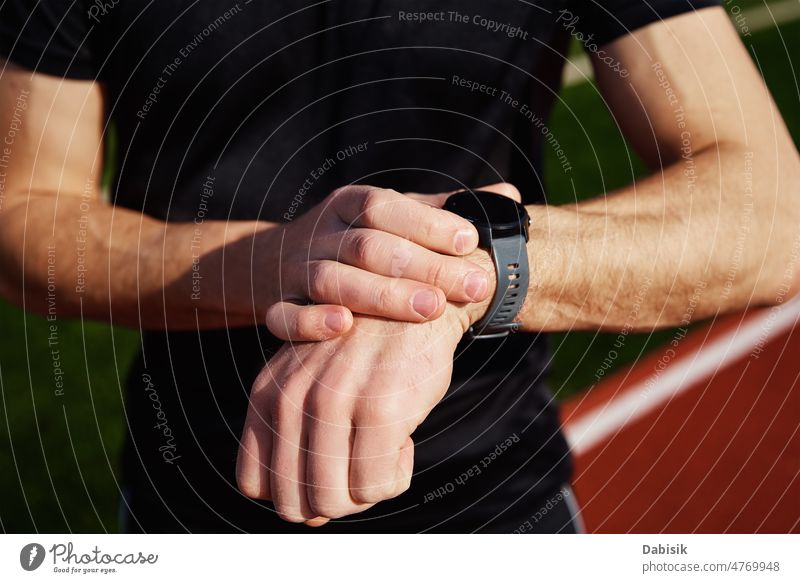 Mann benutzt Fitnessuhr im Stadion Sport aussruhen intelligente Uhr Apparatur online Training im Freien Athlet Sportbekleidung Erwachsener Typ Lifestyle