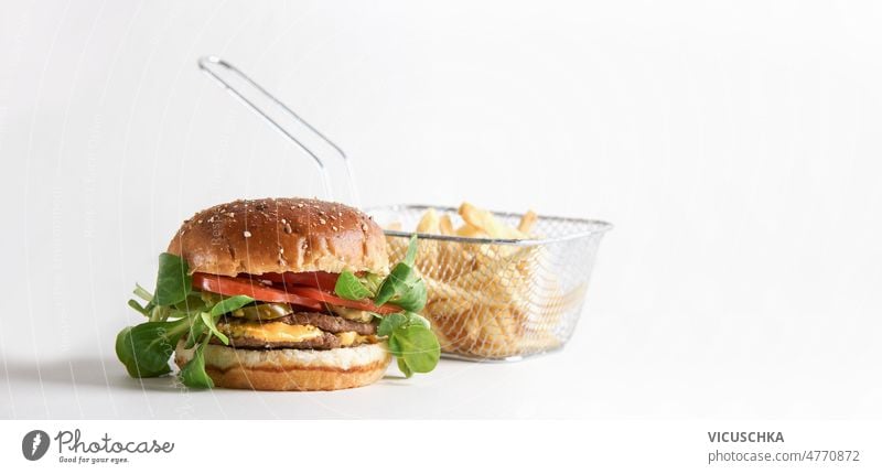 Hamburger mit Rindfleischpatty, Salat, Tomate, Käse, Sauce und Pommes frites weißer Hintergrund amerikanisches Essen zum Mitnehmen Fastfood Pastetchen Saucen
