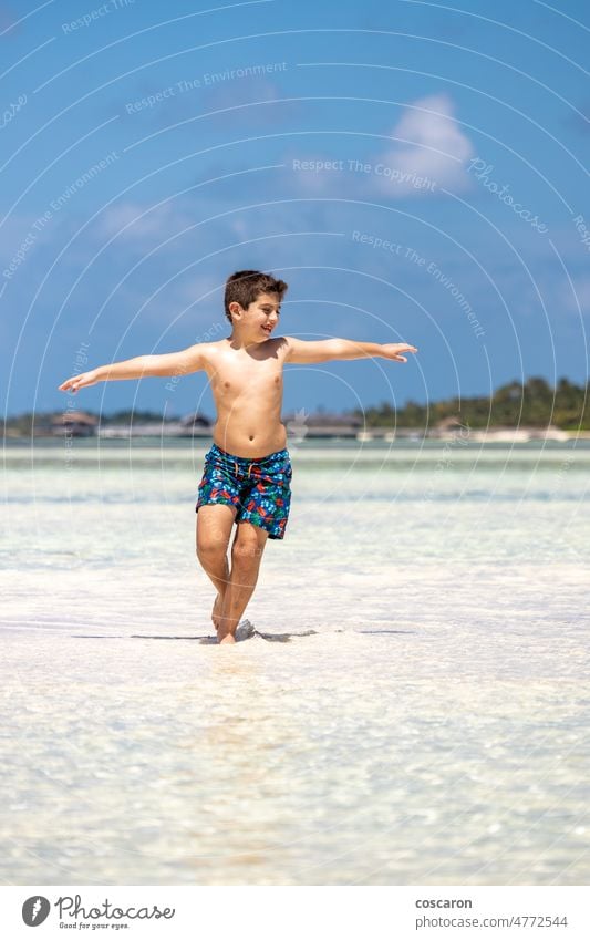 Lustiges Kind läuft und wirft das Wasser eines Strandes mit offenen Armen Waffen Asien Baby blau Junge Kindheit Küste Textfreiraum niedlich Familie Spaß lustig